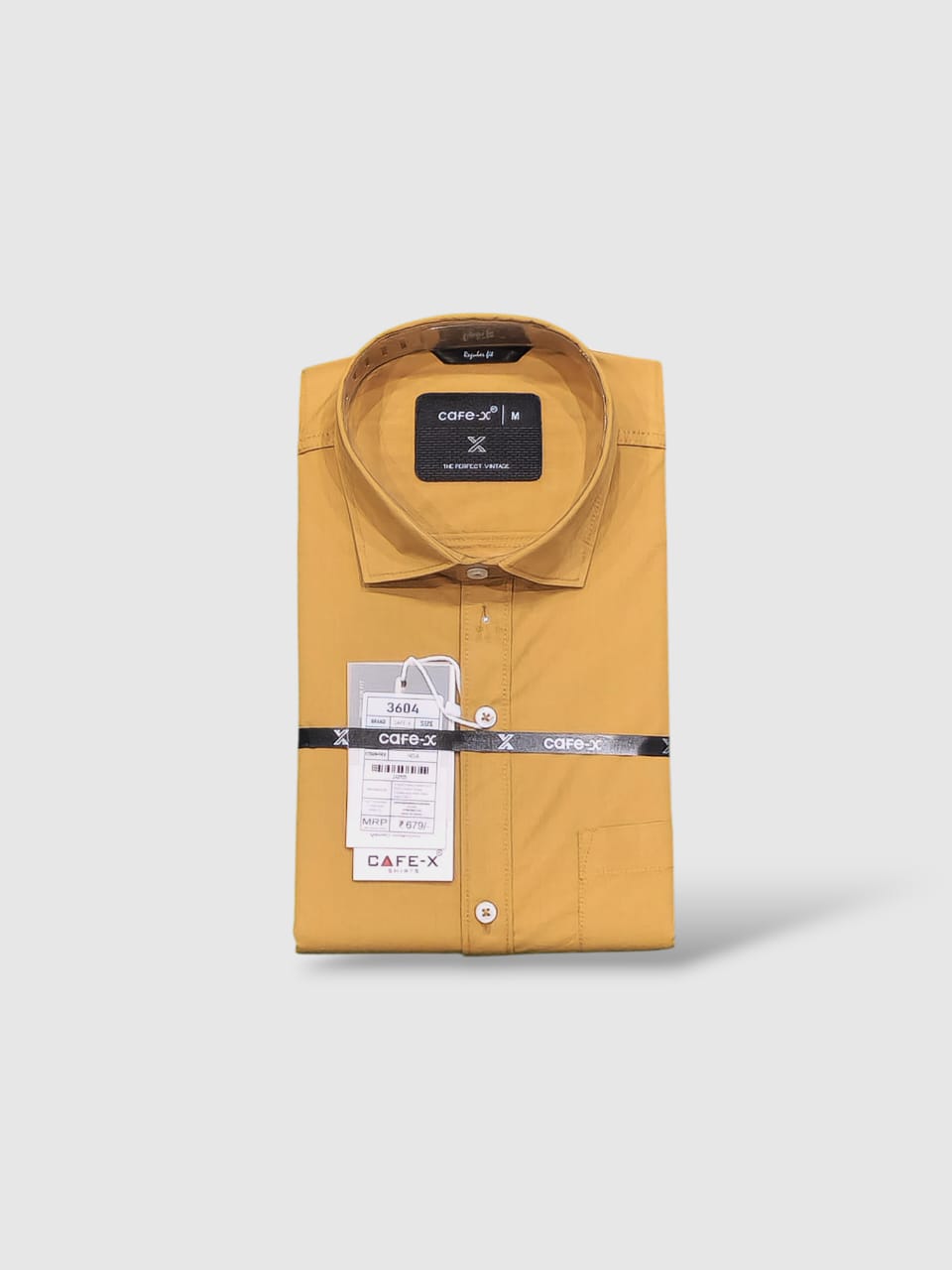 Mustard yellow shirt with a brand label on a light gray background