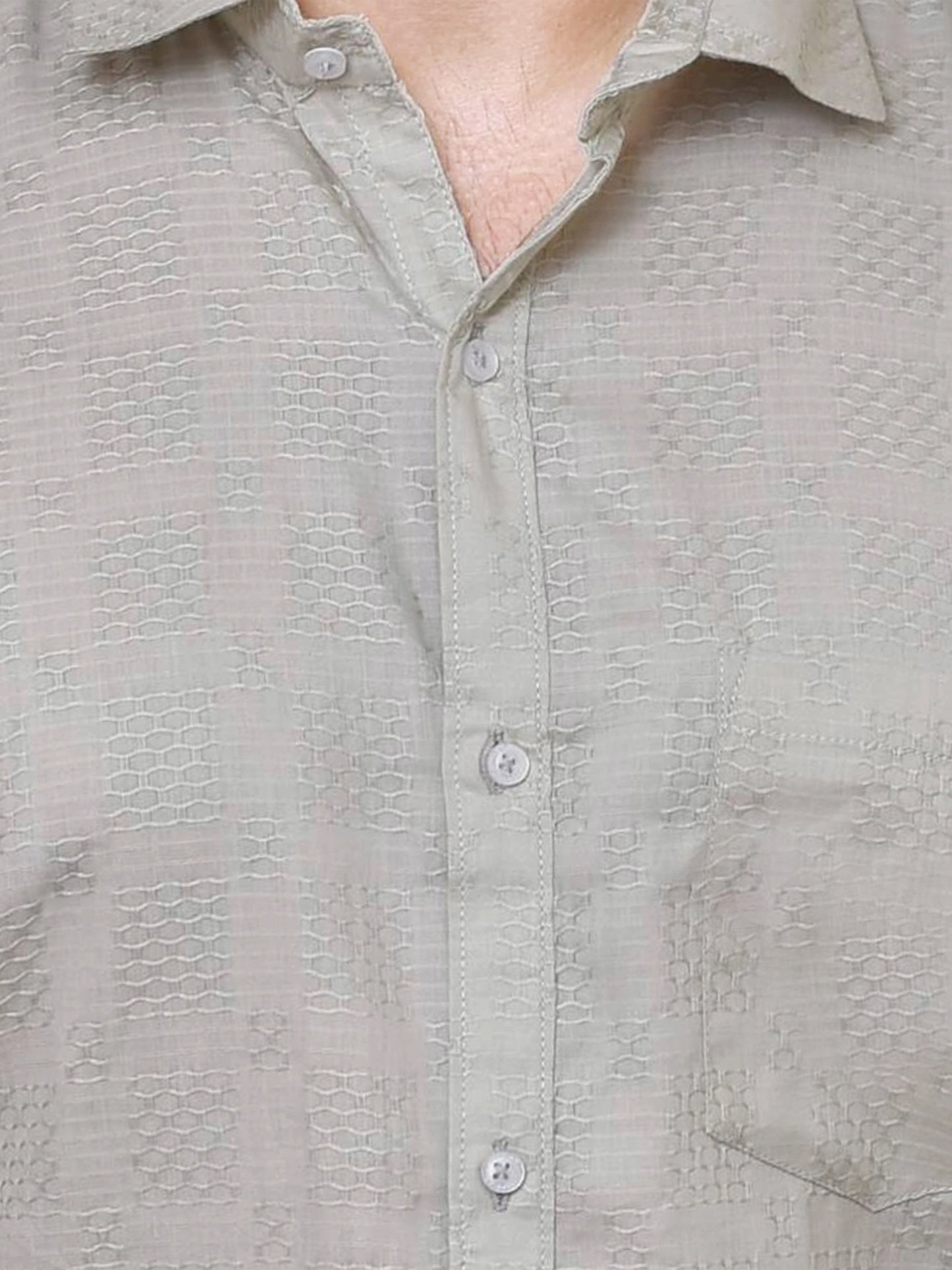 Close-up of a textured sage green dobby shirt with buttons